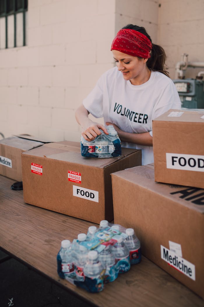 Volunteer packing food and water for charity at an outdoor event, emphasizing community support.